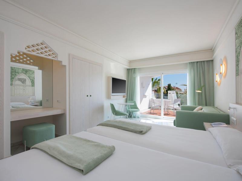 Bright hotel room with double bed, terrace, and modern furnishings.