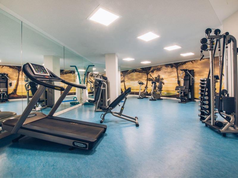 Hotel fitness room with treadmill, dumbbells, and various exercise equipment.