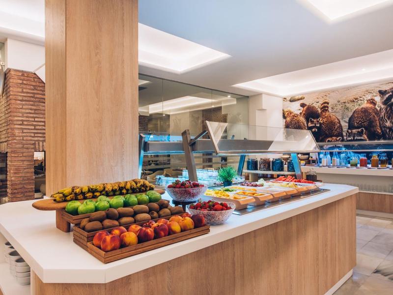Buffet with fresh fruit and various dishes in a modern hotel restaurant.
