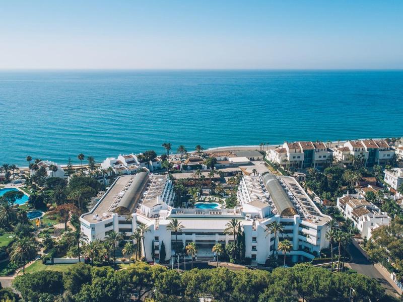 View of a large coastal resort with pools under a clear sky.