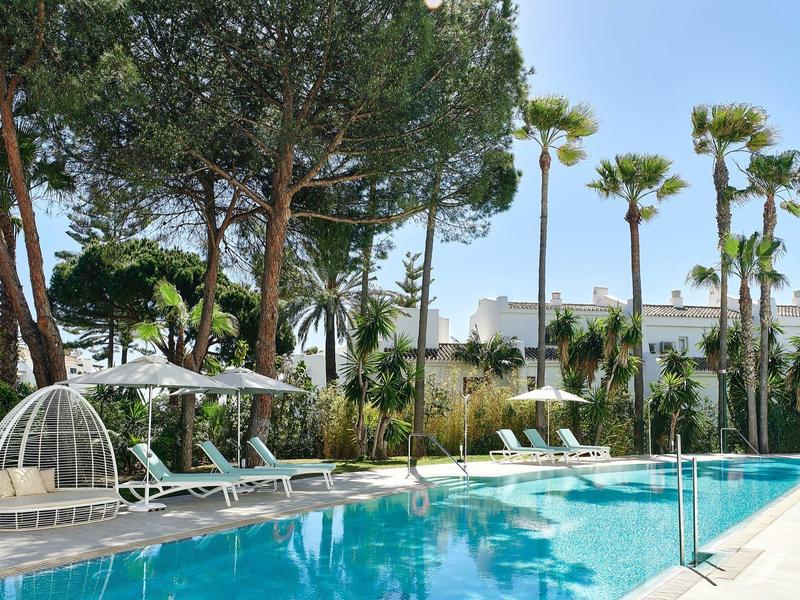 Modern pool area with lounge chairs and palm trees on a sunny day.