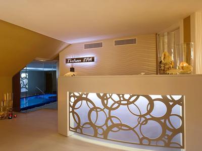 Modern spa area with illuminated reception desk and a pool in the background.