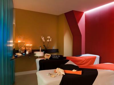 Cozy spa room with two beds, candlelight, and a relaxing ambiance.