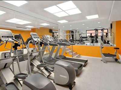 Nowoczesny sprzęt fitness w jasnej, dobrze oświetlonej siłowni z pomarańczowymi ścianami.