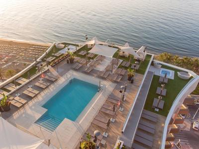 Luxury rooftop terrace with pool and seating areas by the sea.