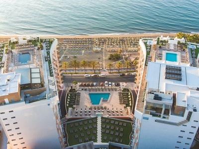 Aerial view of a resort complex with pools, buildings, and direct beach access.