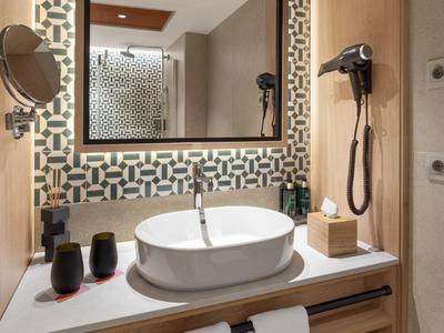Modern bathroom with sink, mirrors, and hairdryer in a hotel room.