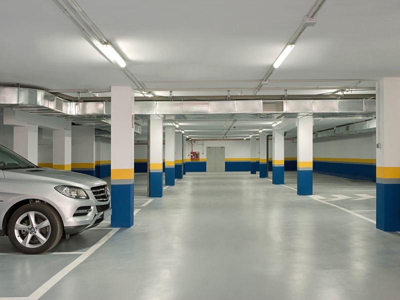 Spacious, well-lit underground parking with white pillars and marked spaces.