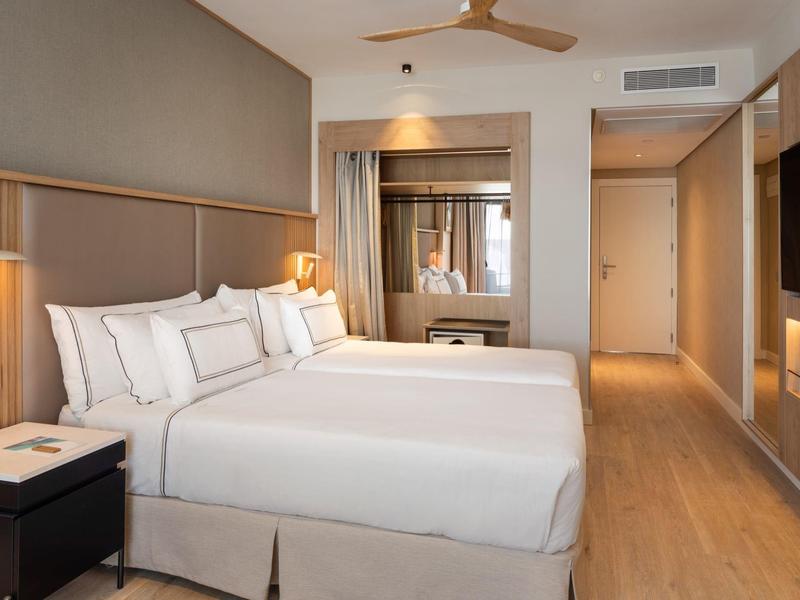 Modern hotel room with double bed, nightstands, air conditioning, and flat-screen TV.