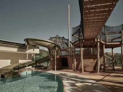 Area piscina moderna con scivolo d'acqua e struttura per arrampicata sotto cielo limpido.