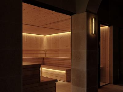 Area sauna scura con panche in legno e luce calda indiretta.