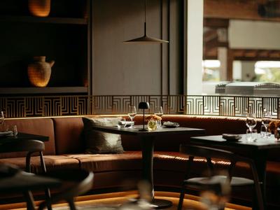 Lounge elegante con mobili in legno scuro e sedie imbottite confortevoli in luce calda.