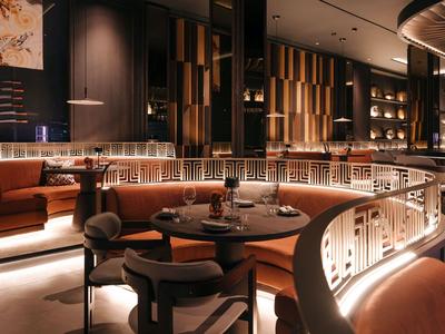 Ristorante moderno in hotel con illuminazione calda, tavoli rotondi e sedute eleganti.
