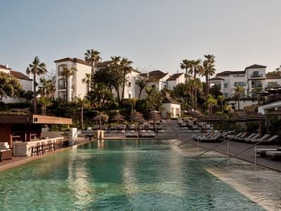 Piscina moderna dell'hotel con lettini e palme sotto un cielo limpido.