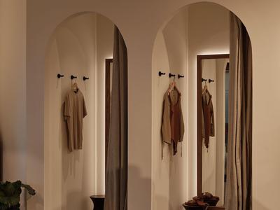 Corridoio elegante di hotel con illuminazione soffusa, tende e ganci per cappotti su porte arrotondate.