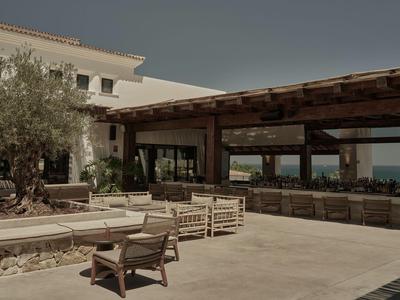Un ampio spazio esterno di un hotel con mobili in legno e vista sul mare.