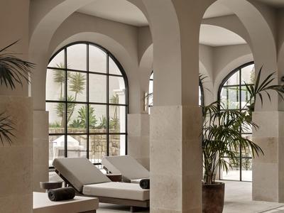 Piscina interna di lusso con grandi archi, lettini e piante in un interno di hotel.