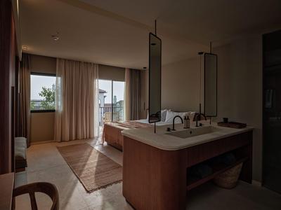 Nowoczesny pokój hotelowy z podwójnym łóżkiem, dużym oknem i umywalką z lustrem.