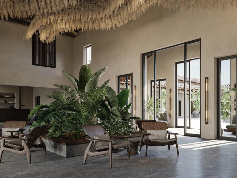 Zona de descanso de hotel iluminada con isla de plantas y mobiliario moderno.