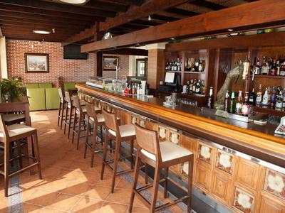 Langgestreckte Bar mit Holzmöbeln, zahlreichen Barhockern und Regalen voller Flaschen.