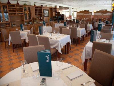 Helles, großes Restaurant mit weißen Tischdecken und bequemen braunen Stühlen, sauber und ordentlich.