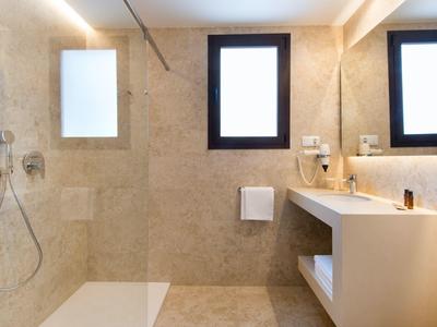 Helles Badezimmer mit beiger Fliesenwand, großer Dusche, zwei Fenstern und modernem Waschbecken.