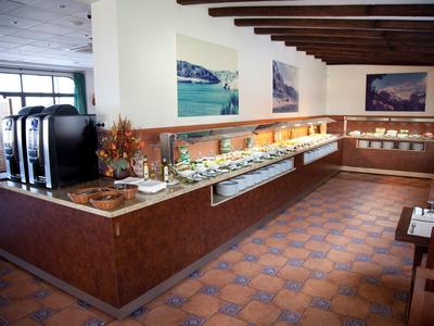 Buffet mit verschiedenen Speisen auf Marmorplatten in einem Raum mit Holzdeckenbalken.