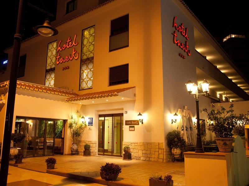 Exterior view of a brightly lit hotel at night with warm lighting and entrance area.