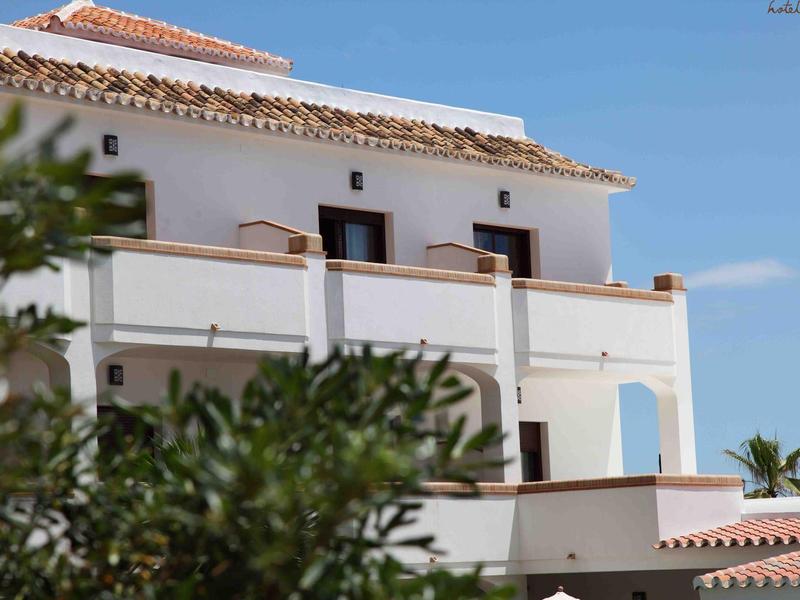 Hotel building with white walls and rooftop terrace under blue sky