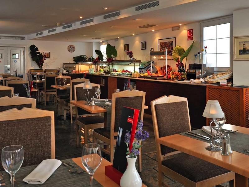 Helles Restaurant mit gedeckten Tischen, Stühlen, Kerzen und Dekoration in warmen Farben.