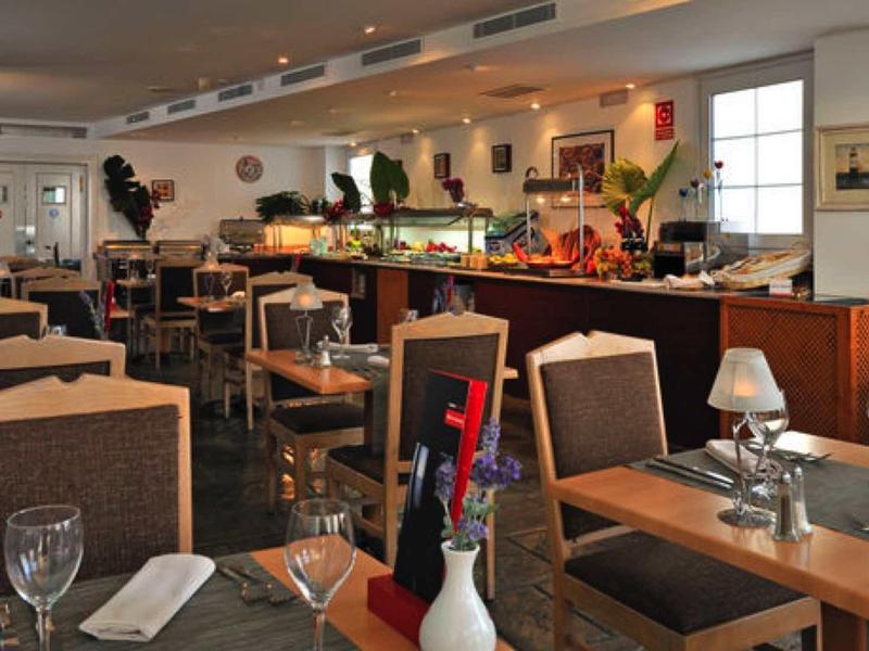 Großes, helles Restaurant mit vielen Holztischen, braunen Stühlen und dekorativen Blumen.