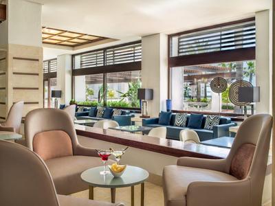 Moderne Lounge mit bequemen Sesseln, kleinen Tischen und großen Fenstern mit Außenblick.