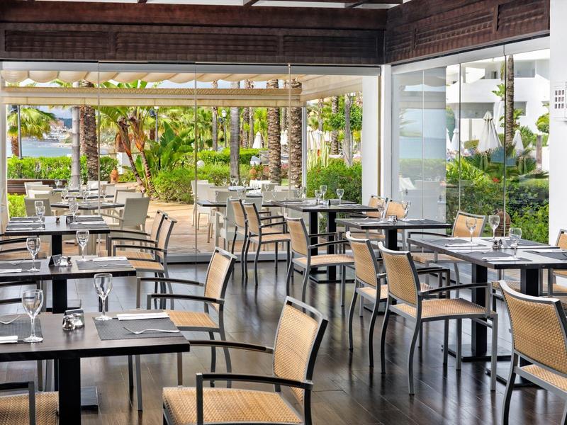 Leeres, helles Café mit Holzstuhl und schwarzen Tischen, Blick auf grüne Außenanlage.