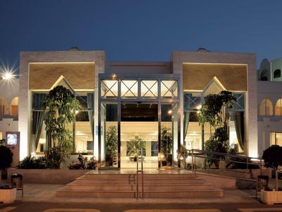 Elegantes Hotelgebäude bei Nacht mit beleuchtetem Eingang und Palmen