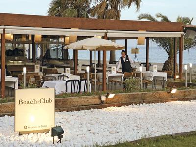 Strandclub mit gedeckten Tischen und Sonnenschirm am Meer