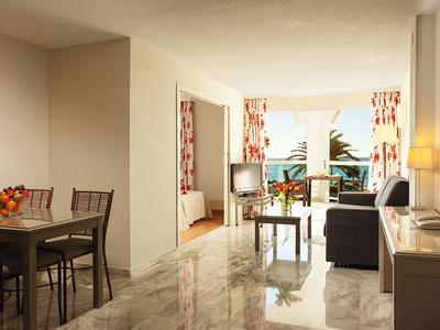 Helles Wohnzimmer mit Essbereich, Sofa, TV und Zugang zu einem Balkon mit Meerblick.