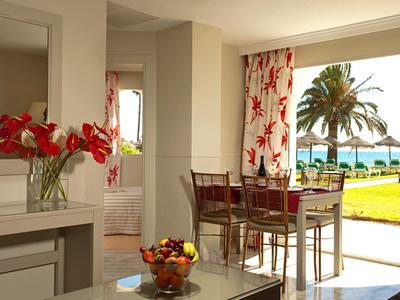 Heller Essbereich mit Tisch, Stühlen und Blick auf eine Terrasse und den Garten mit Palmen