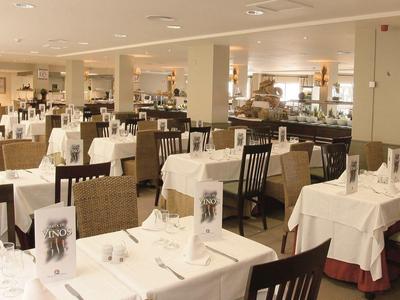 Großer Speisesaal mit weißen Tischdecken und Holzstühlen in einem Hotel.