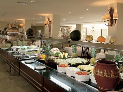 Buffet mit Salaten und Gemüse in einem hellen Restaurant mit dekorativen Kürbissen.