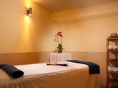 Gemütlicher Massageraum mit beleuchtetem hellen Raum und frischer Orchidee auf dem Tisch.