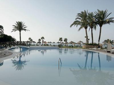 Großer Pool mit Palmen und Liegestühlen in einem sonnigen Hotelresort