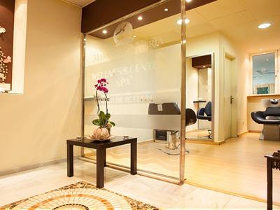 Moderne Empfangshalle mit Glaswand, Blume auf Tisch und gemütlichen Sitzgelegenheiten.