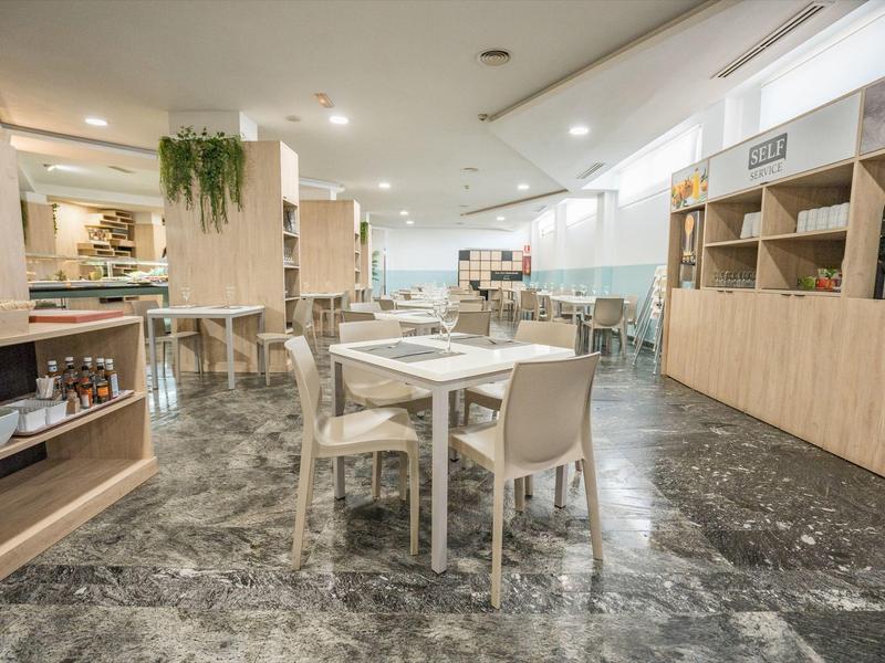 Heller, moderner Speiseraum mit weißen Möbeln, Marmorfliesen und Holzregalen an der Wand.