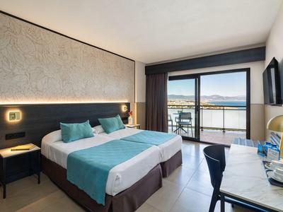 Modern hotel room with double bed, desk, and large window overlooking the lake.