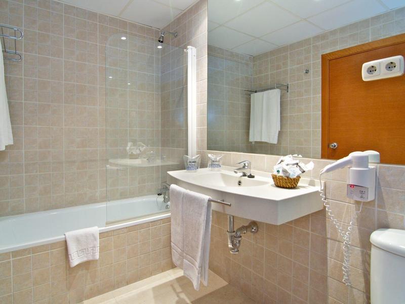 Ein modernes Badezimmer mit Badewanne, großem Spiegel, Waschbecken und weißen Handtüchern an Wänden.