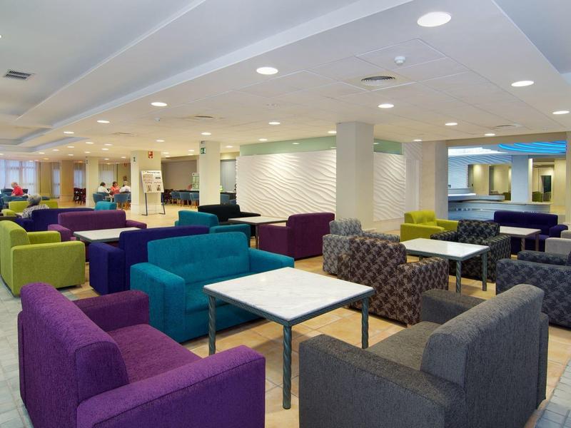 Großer, heller Raum mit bunten Sofas und Tischen, ruhige moderne Lounge-Atmosphäre.