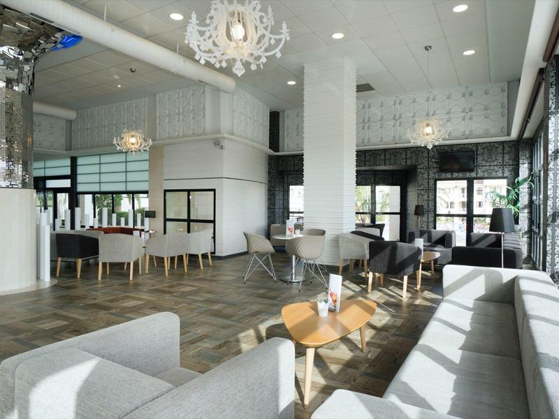 Heller, moderner Wohnraum mit großen Fenstern, weißen Wänden, Möbeln und Parkettboden.