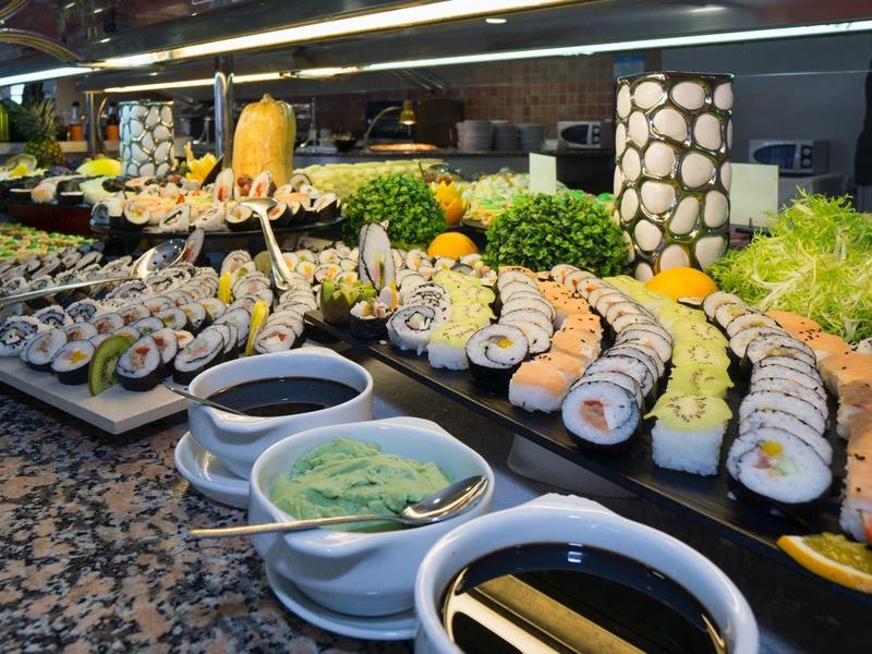 Buffet mit verschiedenen Sushirollen, Saucen, Wasabi und frischem Gemüse auf Granitplatte.