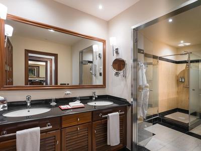 Modernes Badezimmer mit großem Spiegel, schwarzer Arbeitsplatte und begehbarer Glaskabine.