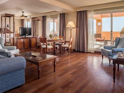 Helles Wohnzimmer mit Holzboden, Sesseln, Sofa, Couchtisch, Esstisch und großer Fensterterrasse.